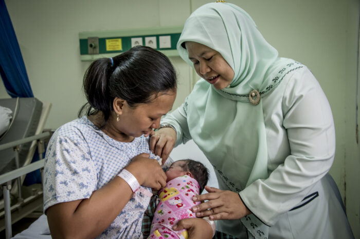 Midwives working the Islamic hospitals in Jakarta: RS is Rumah Sakit which means hospital RS Islam Jakarta Pondok Kopi Midwife Een Sumarni pictured, working with Kurniasih, 32 years old with her 3rd child, baby girl, Zahra Avra, one day old, with breast feeding.