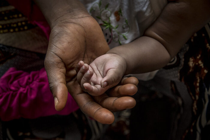 A mother holds the hand of her five-month old child in her palm 